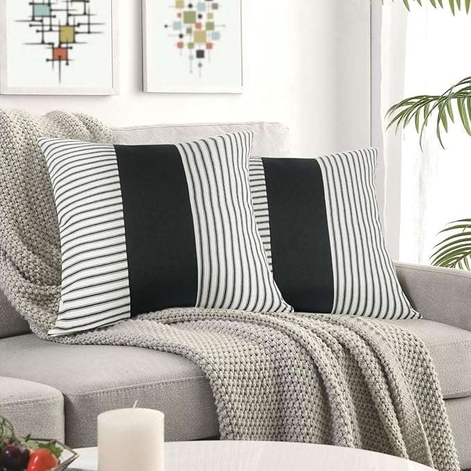 Farmhouse-style black and white striped patchwork throw pillow cover displayed on a couch, ideal for modern rustic living room decor and mixing with other accent pillows.
