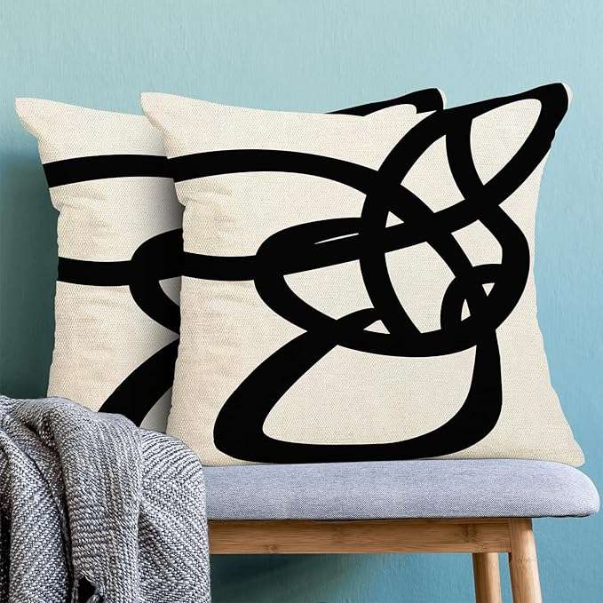 Farmhouse-style black and white striped patchwork throw pillow cover displayed on a couch, ideal for modern rustic living room decor and mixing with other accent pillows.