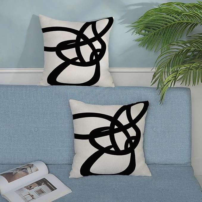 Farmhouse-style black and white striped patchwork throw pillow cover displayed on a couch, ideal for modern rustic living room decor and mixing with other accent pillows.
